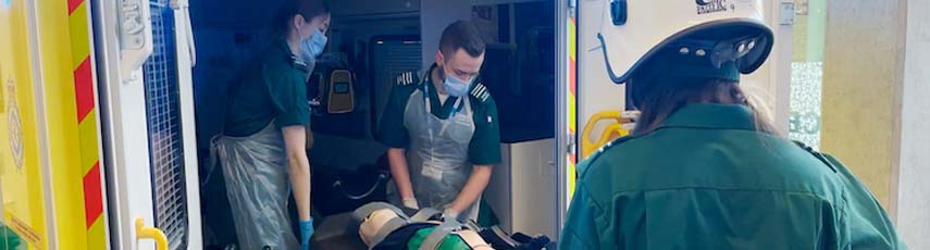 Mock up scene of paramedics pushing patient into ambulance vehicle