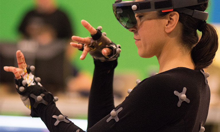 A woman wearing a black leotard with sensors attached to it dances.