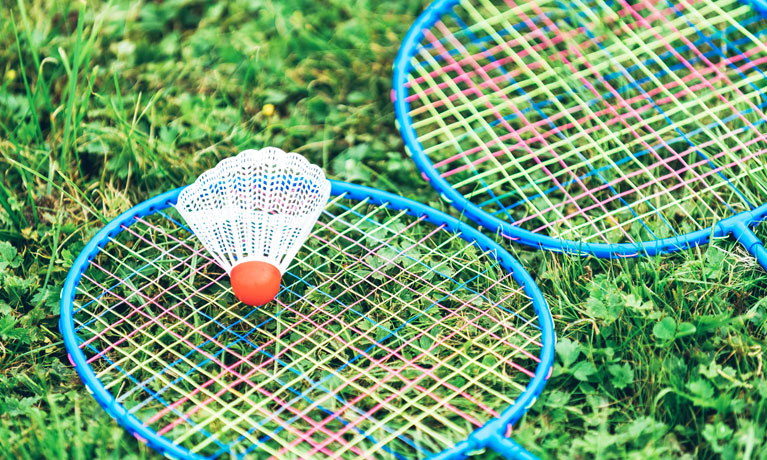 Two badminton rackets and a shuttlecock lying on grass