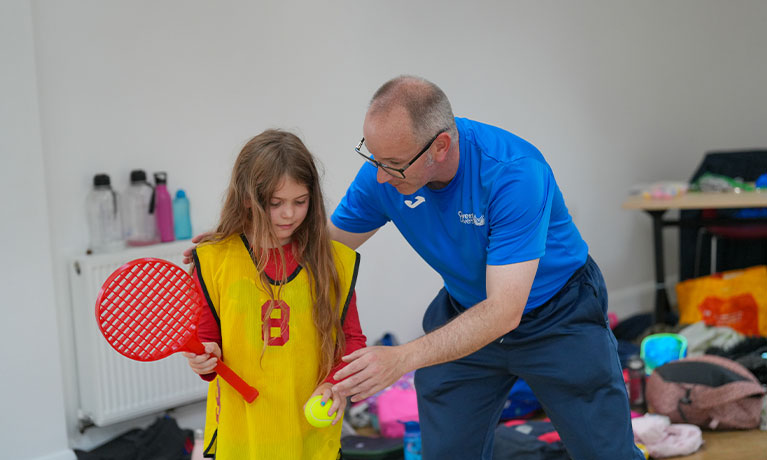 Professor Mike Duncan teaching a child how to play tennis