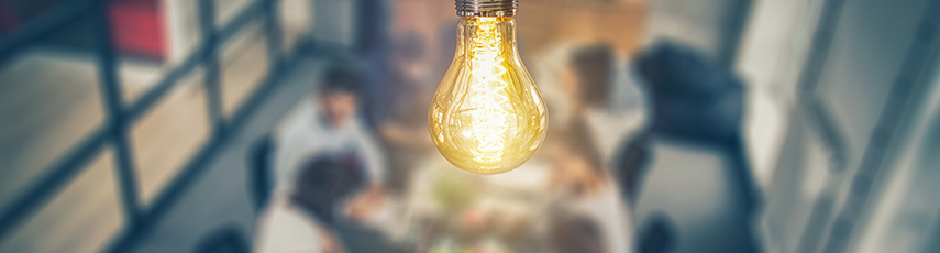 Glowing lightbulb over a table of young people