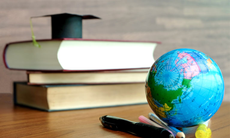 Books on table with small globe in foreground.