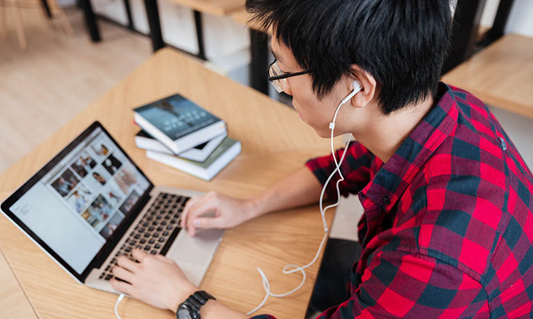 a man wearing headphones leans over a laptop