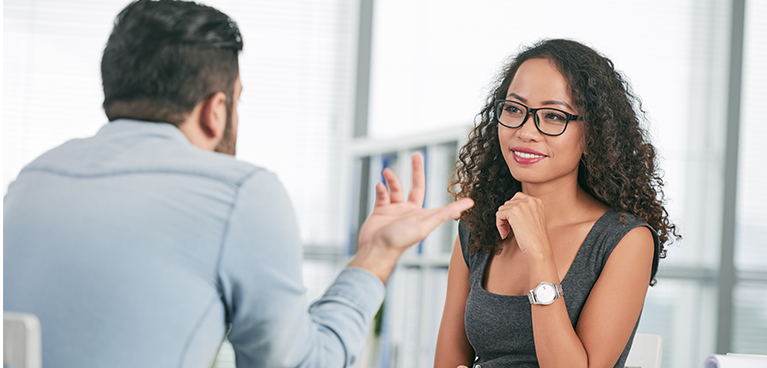 two business professionals talking, one turned away from camera