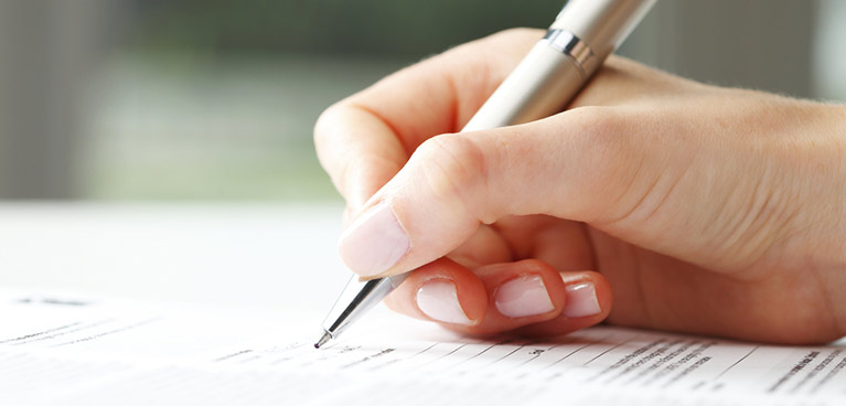 A hand holding a pen writing on piece of paper