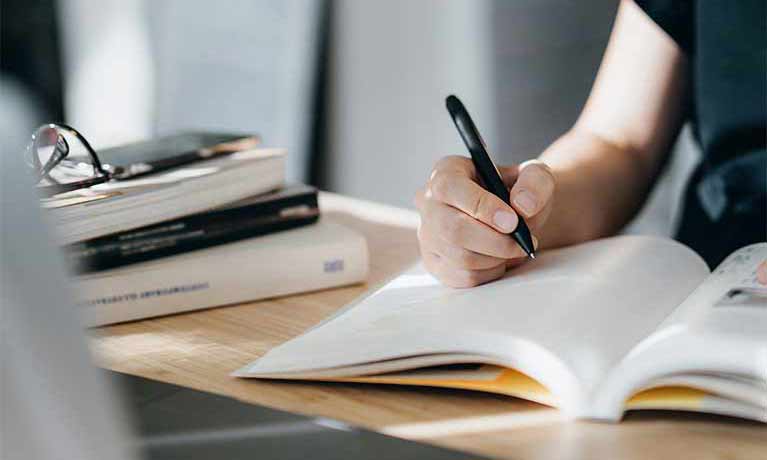 close up of a person writing in a book 