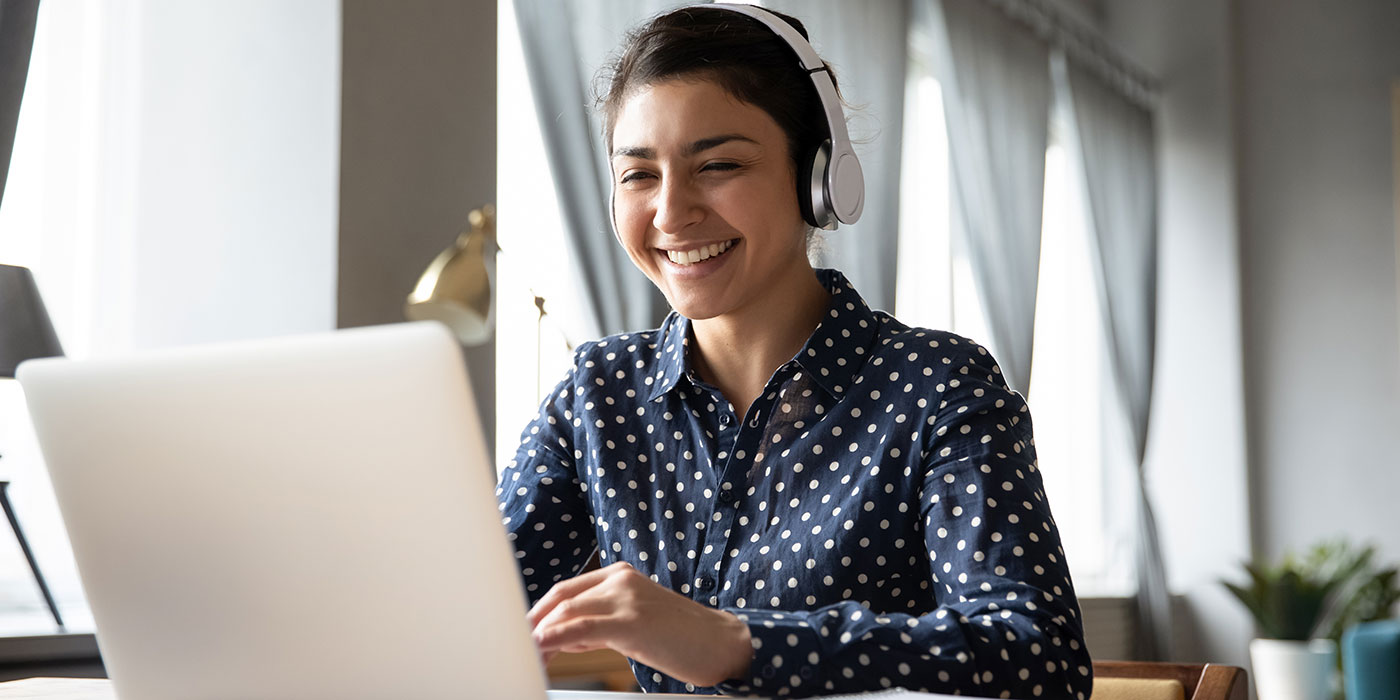 Woman working on a laptop wearing headphones