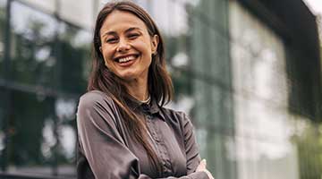 smiling business woman standing outside a glassed building