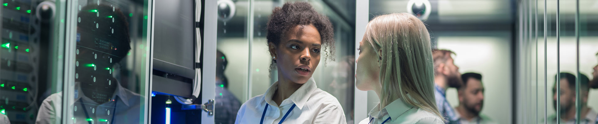 Two women working in a data centre with rows of server racks.