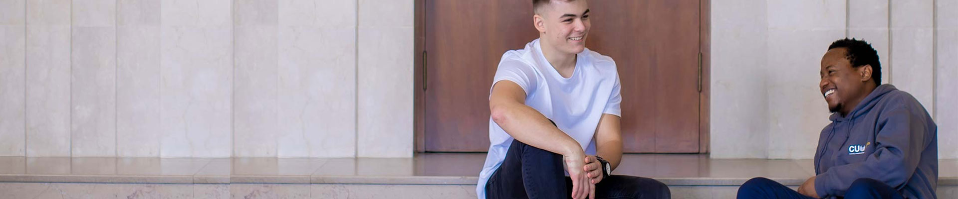 Two people sitting on the stairs outside of building