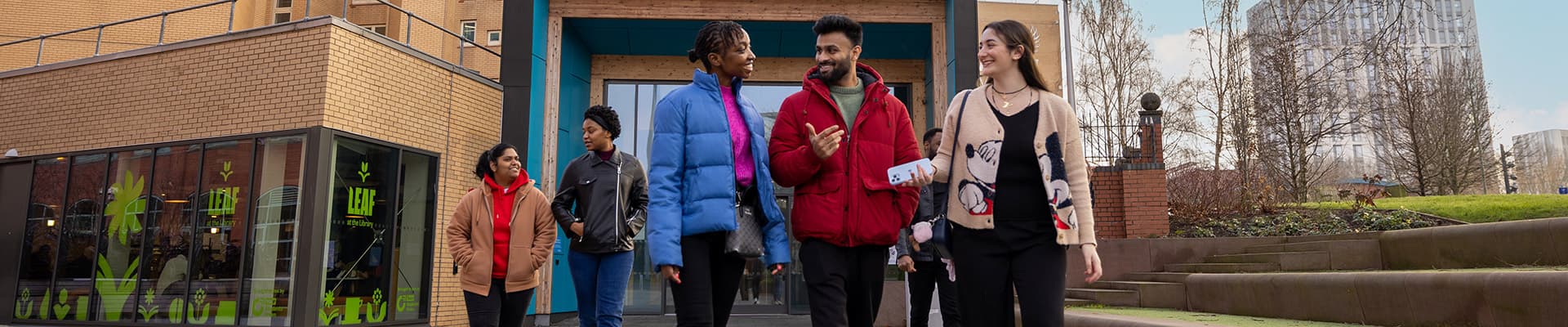 Three students stood infront of the library talking