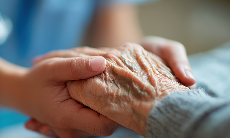 A nurse holding an elderly persons hand