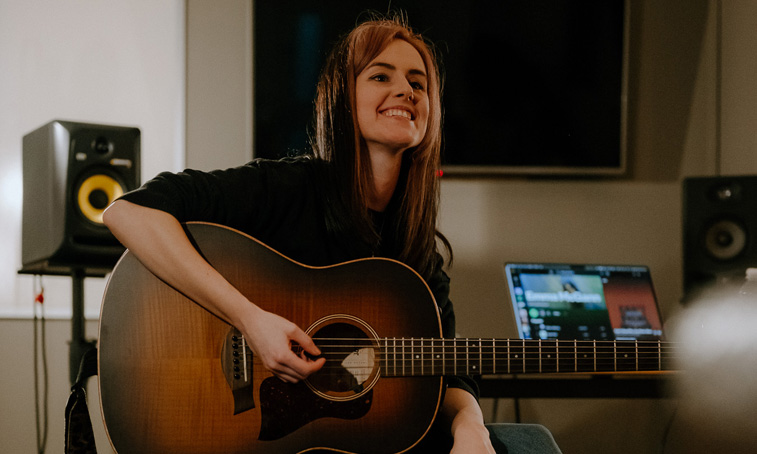 Emma McGann smiling with a guitar