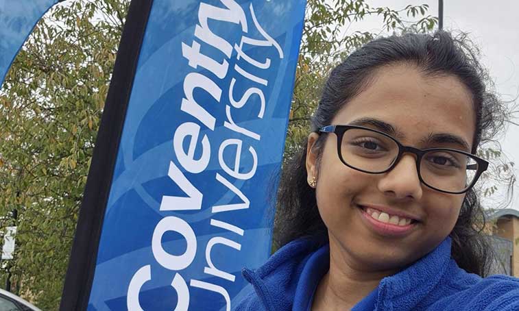 Sri Anshula Chennareddy smiling next to a Coventry University banner
