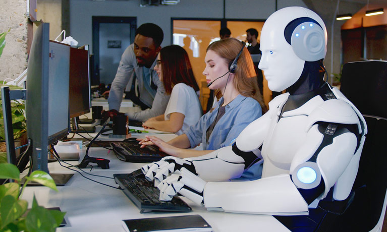 A robot typing on a keyboard at acomputer among people in an office.