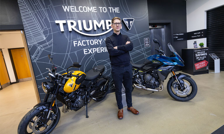 Gavin Hardman smiling next to a motorbike at Triumph
