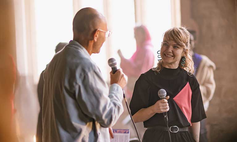 Sam holding an microphone in an interview