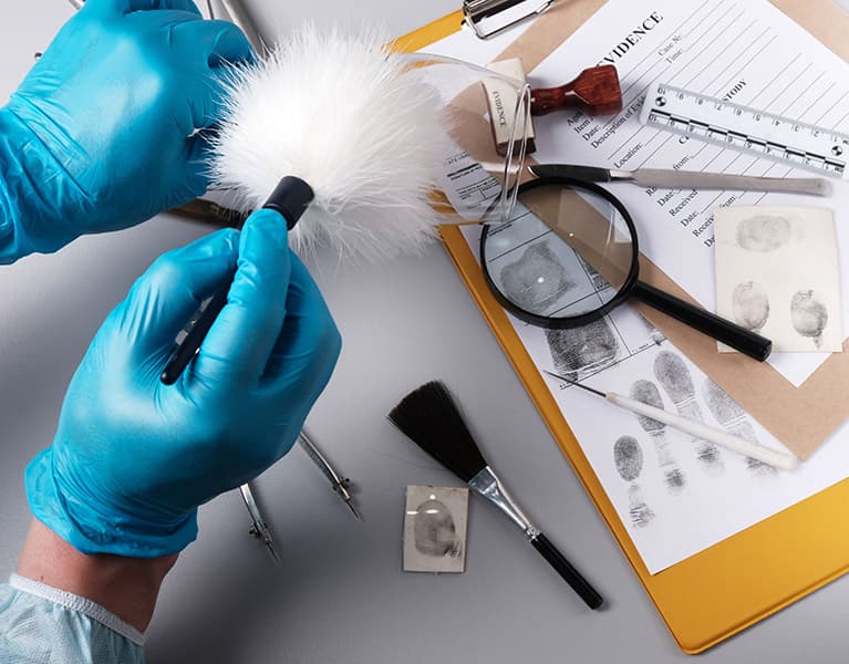 hand wearing latex glove dusting items for prints