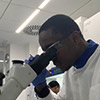Miracle Anyabuaku looking into a microscope