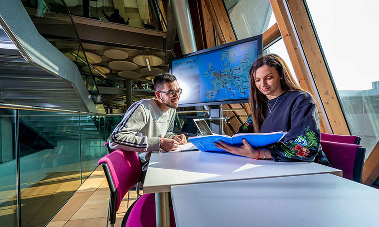 Two students sat at a table reading a book