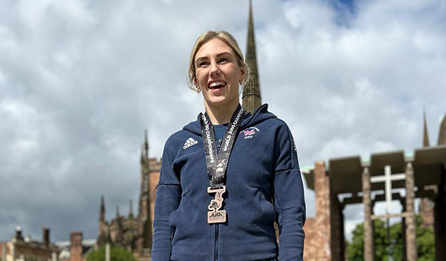 Emma Reid wearing her Commonwealth medal in front of Coventry Cathedral