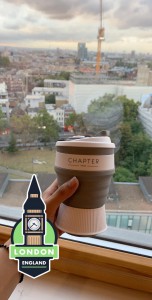 Hand holding a coffee in front of a skyline