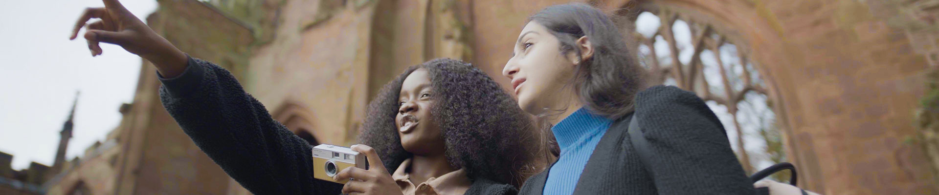 Two female students stood in the cathedral ruins