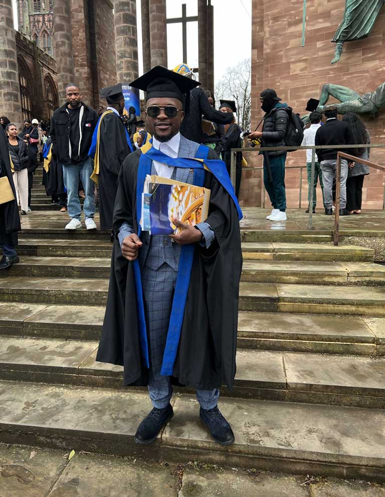 Samson at his graduation, stood outside of Coventry cathedral