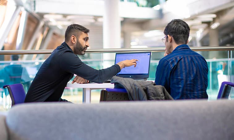 Two people sat together looking at a laptop