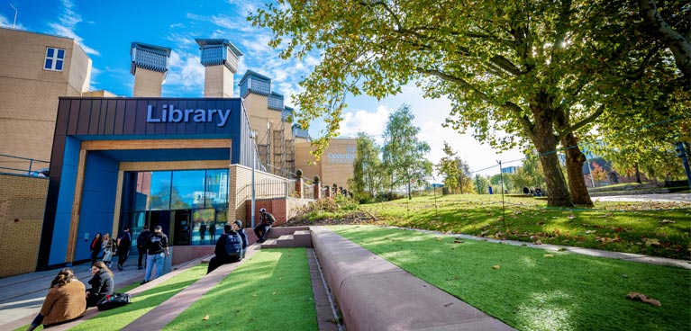 Entrance to the library with students sat nearby