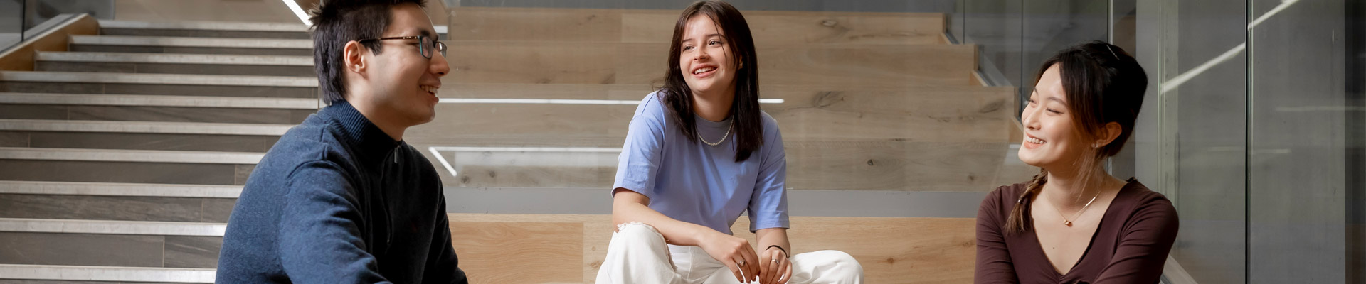 Three international students chatting on a staircase.