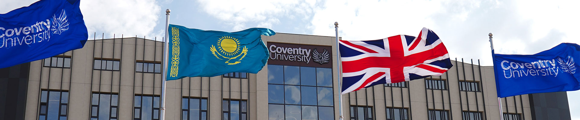 An external view of the Coventry University Kazakhstan campus building, with flags flying outside.
