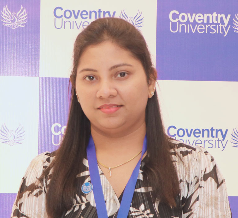 Portrait of Joan Felina Fernandez against a Coventry University banner in the background.