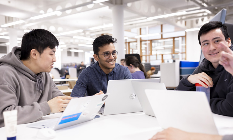 Students using laptops in an open study area.