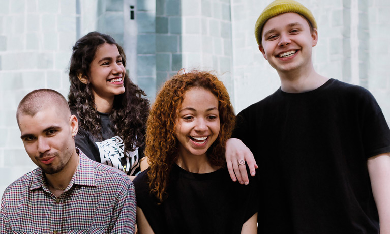 Four students smiling outside in the city.