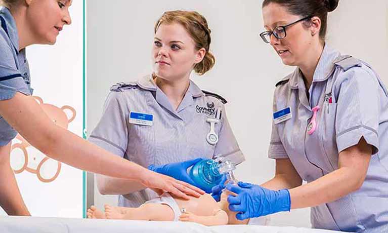 Three nursing students working on a dummy baby 