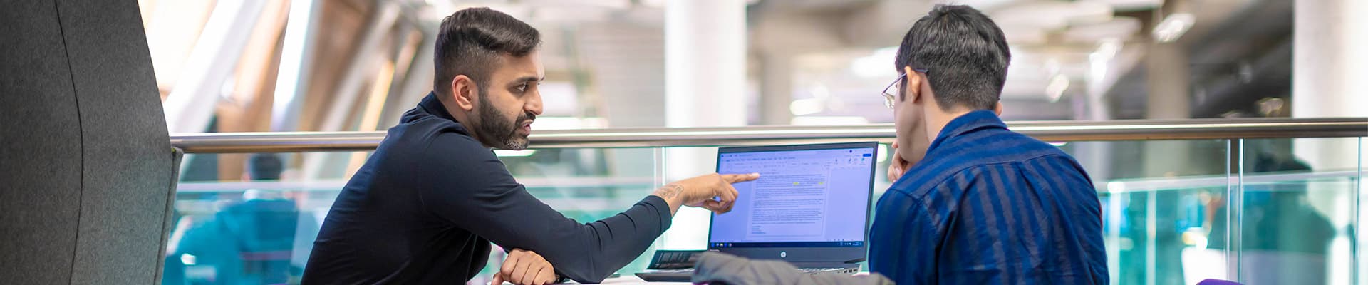 Two people sat next to each other looking at a laptop