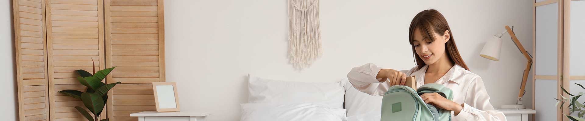 Female student in a bedroom packing a bag