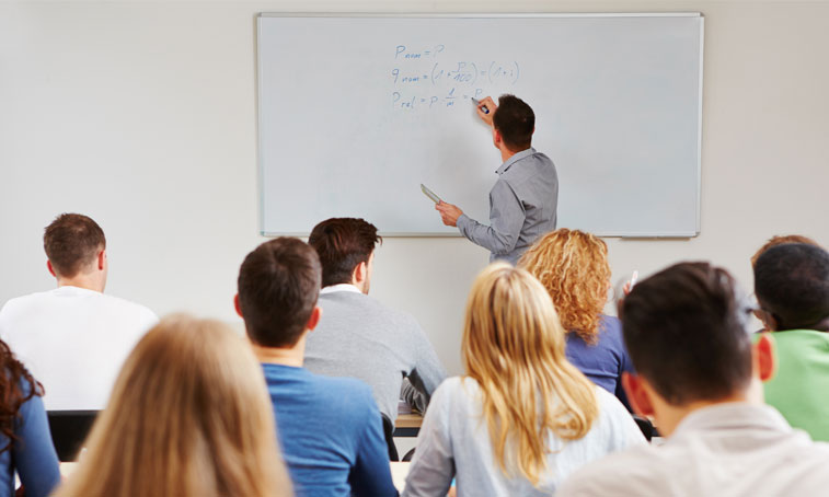 teacher writing on whiteboard in a classroom with students