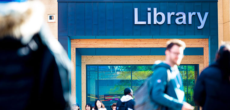 Students walking in and out of the library entrance.