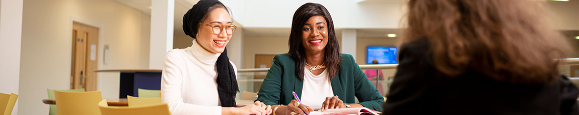 Two smiling women look at a third person facing them