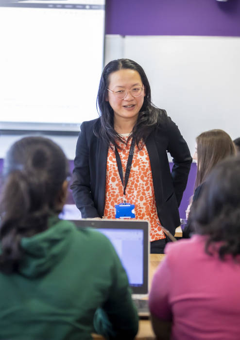 Lecturer stood at the front of a classroom talking to students