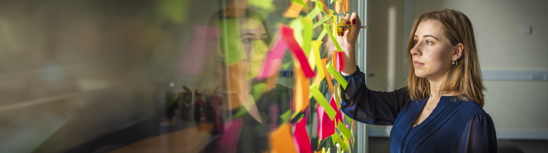 Student arranging postit notes on a perspex screen