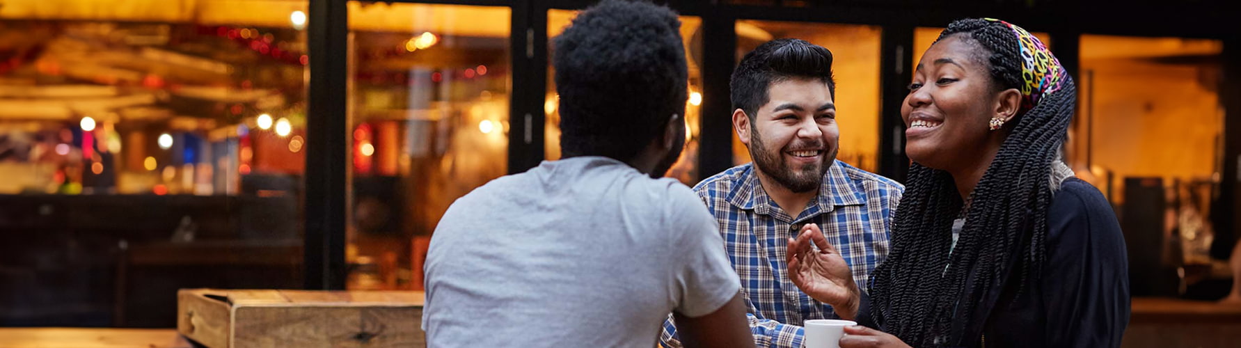 Three students sitting outside a bar laughing