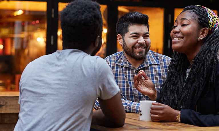 3 smiling students outside a bar 