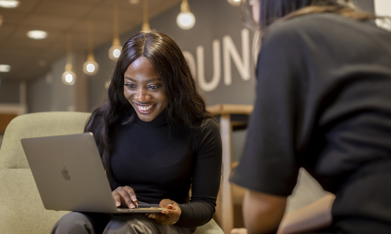 Student smiling while using a laptop.