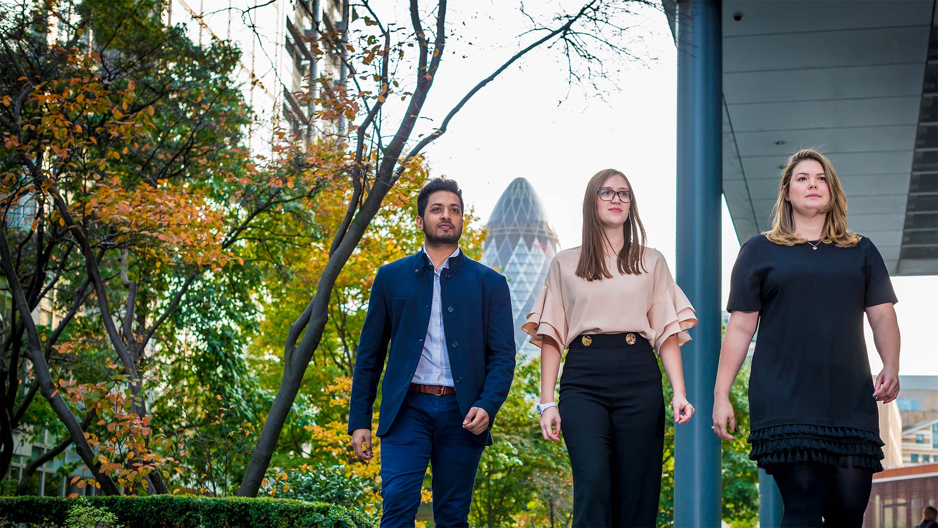 Three students walking through the City of London with the Gherkin Building in the background