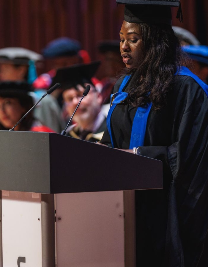 Graduate standing at a podium giving a speech