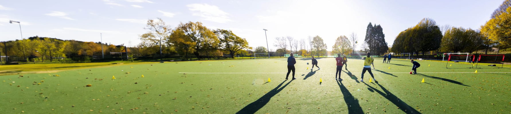 Students training on a football pitch in evening sun