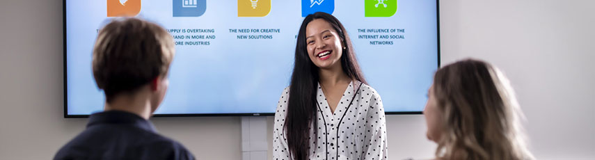 a smiling student looks at two other students faced away from the camera